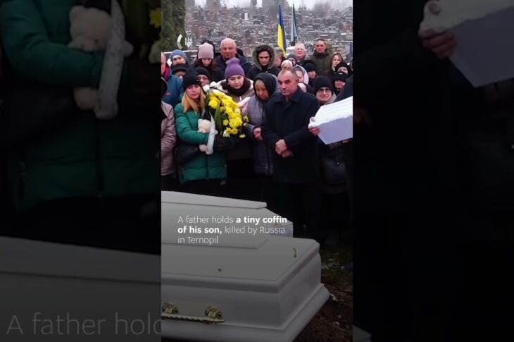 A father gently rocks the small coffin of his one-year-old son.